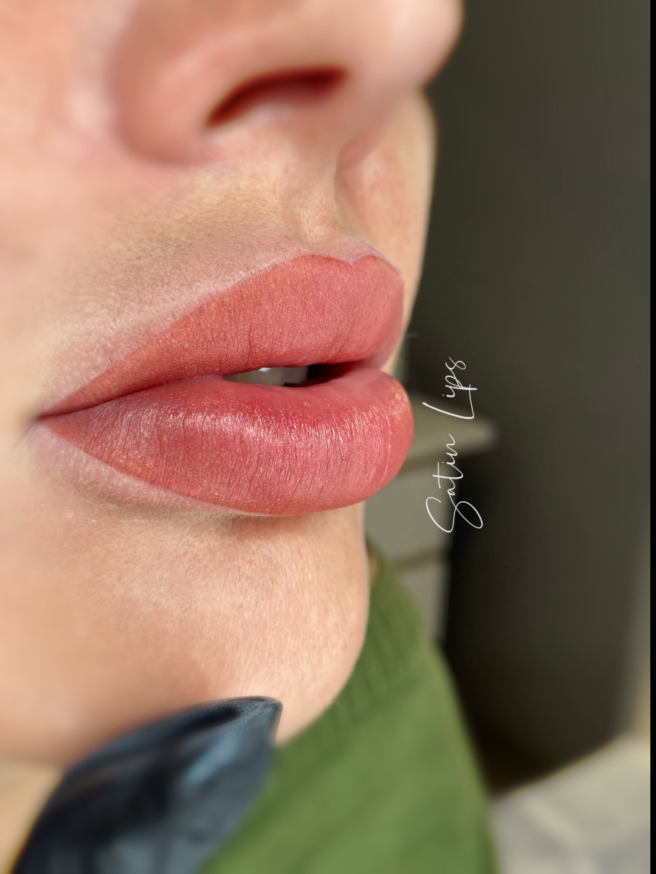 Usta po makijażu permanentnym w ciepłym koralowym odcieniu, z profilu, z podpisem Satin Lips